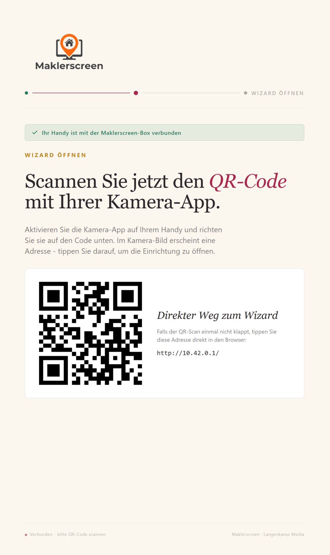 Maklerscreen-Box am Schaufenster-Monitor: das Display zeigt im Einrichtungs-Modus einen grossen QR-Code, mit dem das Smartphone den Setup-Assistenten oeffnet.